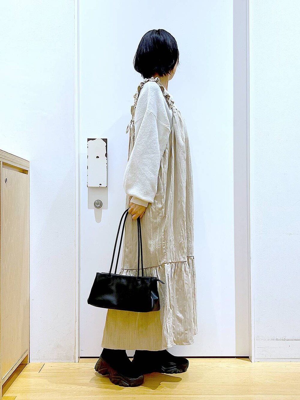 ブラック系のブーツ、ブラック系のトートバッグ、ベージュ系のニット/セーターを着用したレディースの冬コーディネートの4枚目の写真