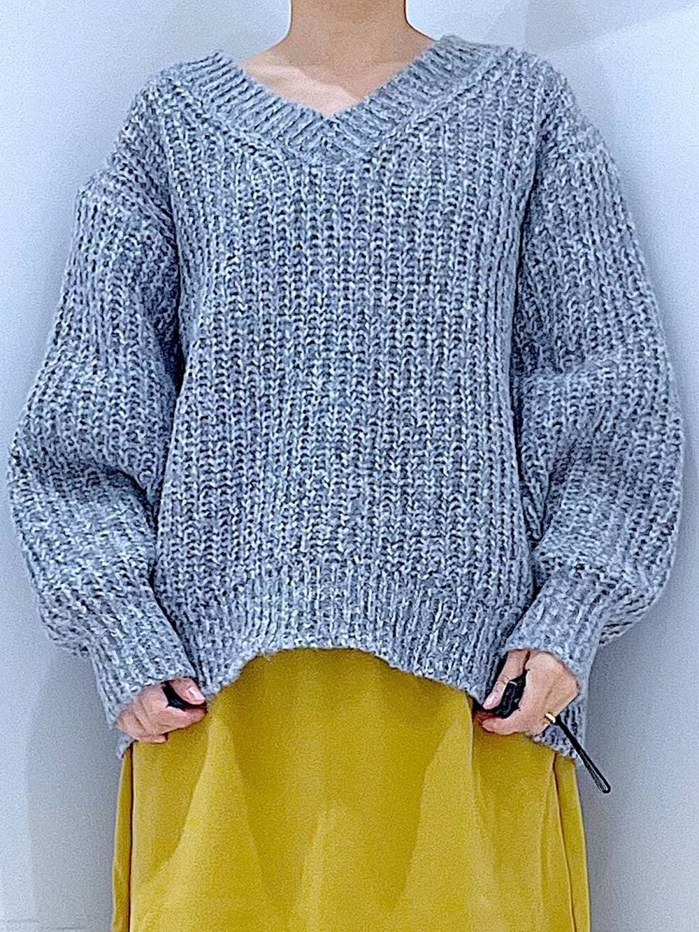 グレー系のニット/セーター、イエロー系のスカート、ブラック系のブーツを着用したレディースの冬コーディネートの7枚目の写真