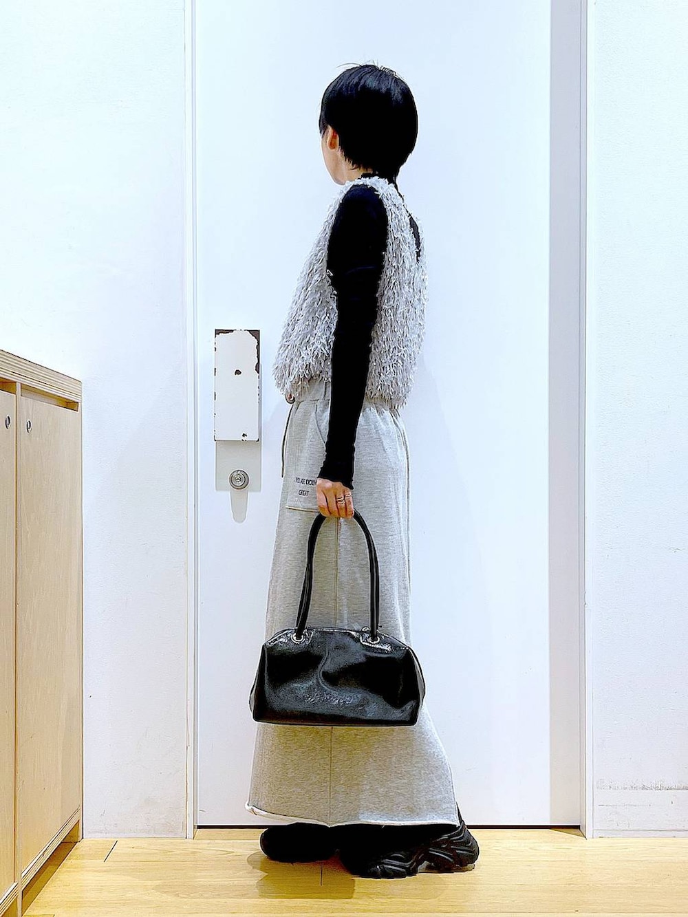 ブラック系のブーツ、ブラック系のTシャツ/カットソー、グレー系のスカートを着用したレディースの春コーディネートの3枚目の写真