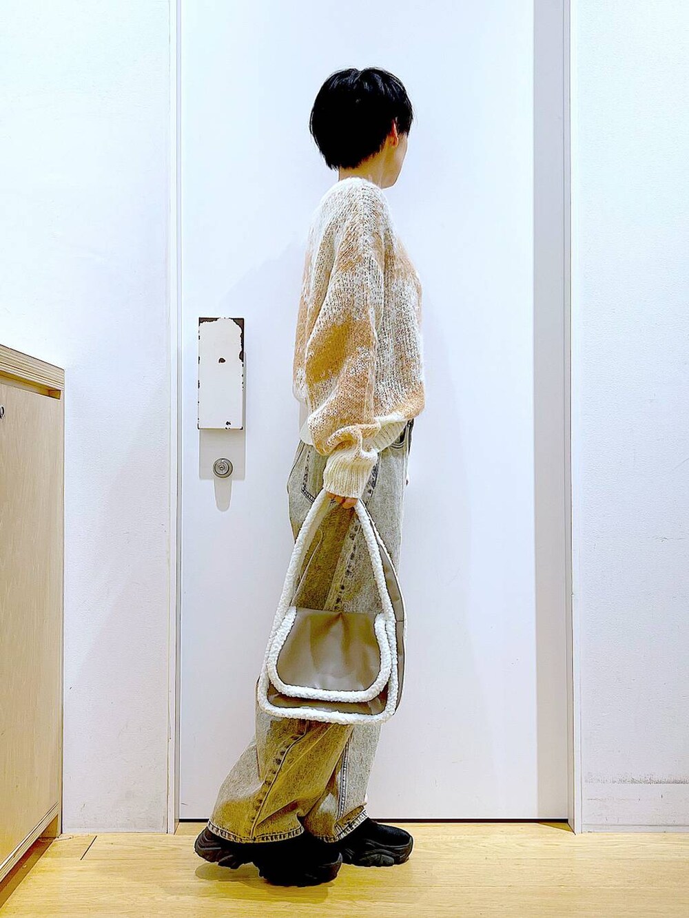 ブラック系のブーツ、ベージュ系のショルダーバッグ、ベージュ系のデニムパンツを着用したレディースの冬コーディネートの4枚目の写真