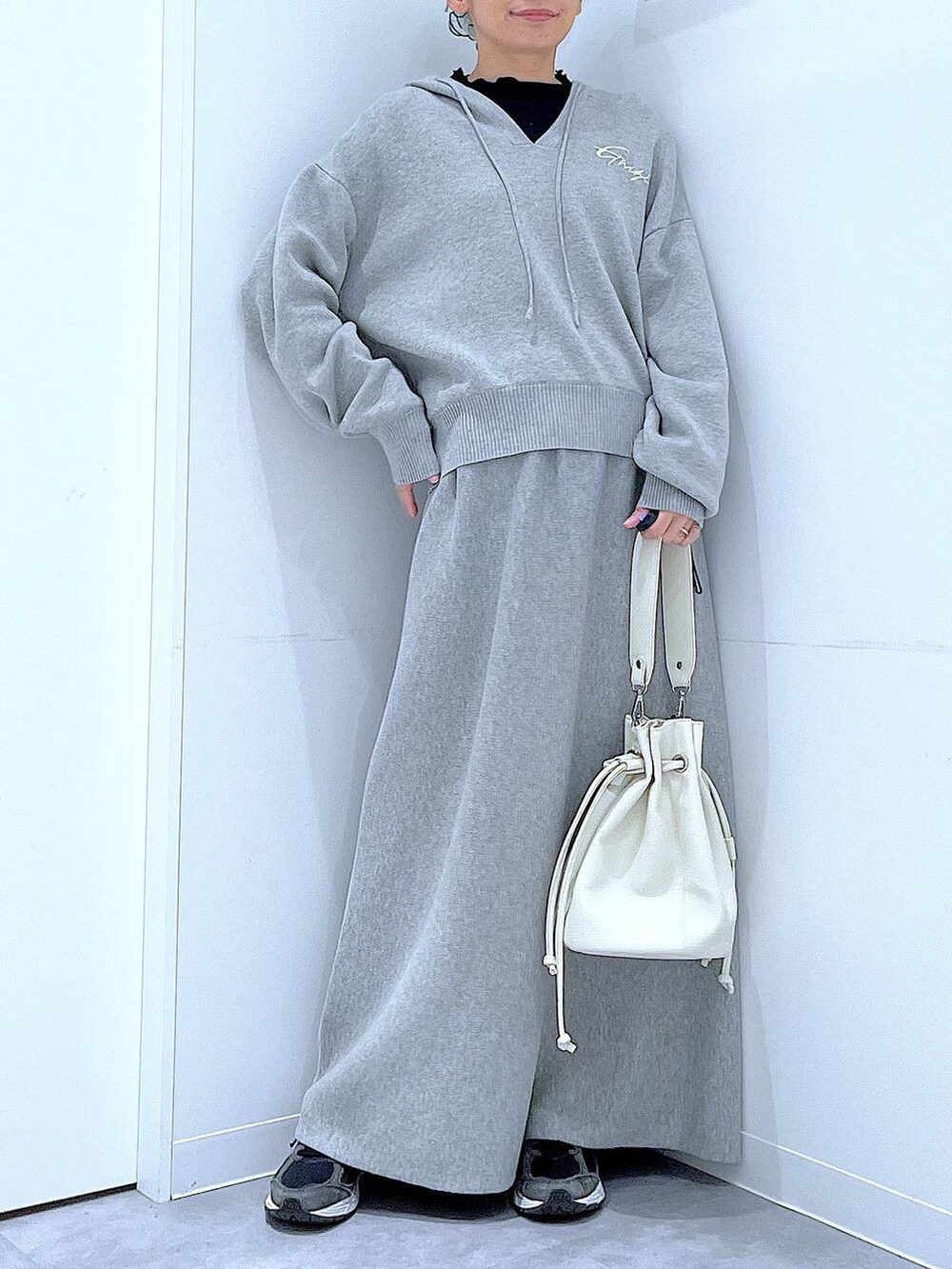 ブラック系のTシャツ/カットソー、グレー系のスカート、ホワイト系のショルダーバッグを着用したレディースの春コーディネートの6枚目の写真