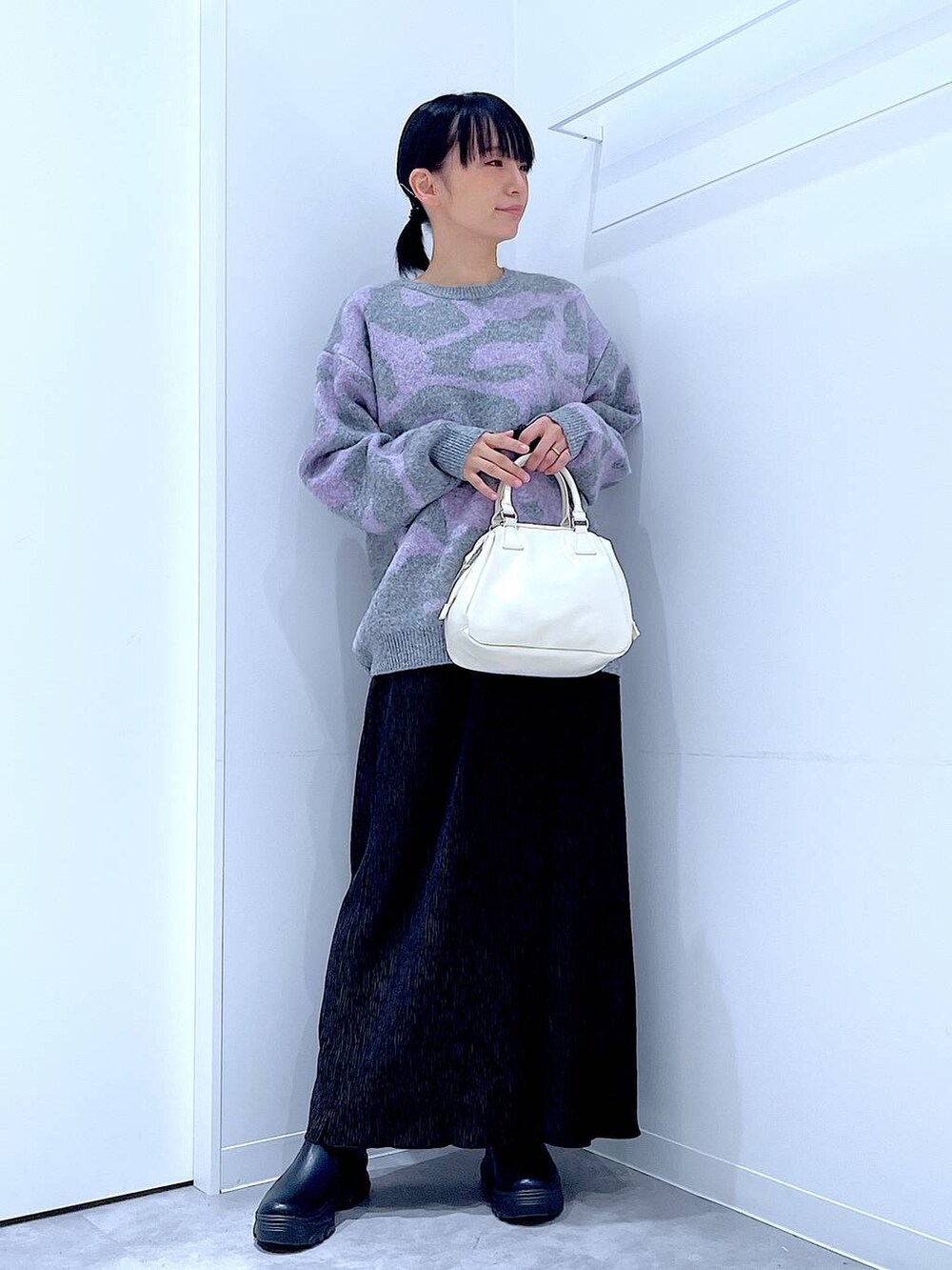 ブラック系のブーツ、グレー系のニット/セーター、ブラック系のスカートを着用したレディースの冬コーディネートの2枚目の写真