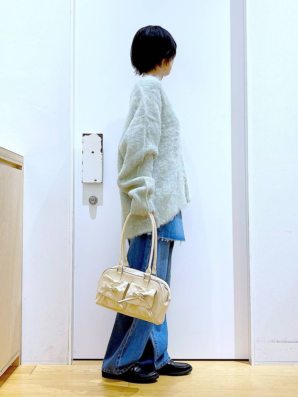 グリーン系のカーディガン/ボレロ、ブラック系のローファー、ブルー系のデニムパンツを着用したレディースの秋コーディネートの4枚目の写真