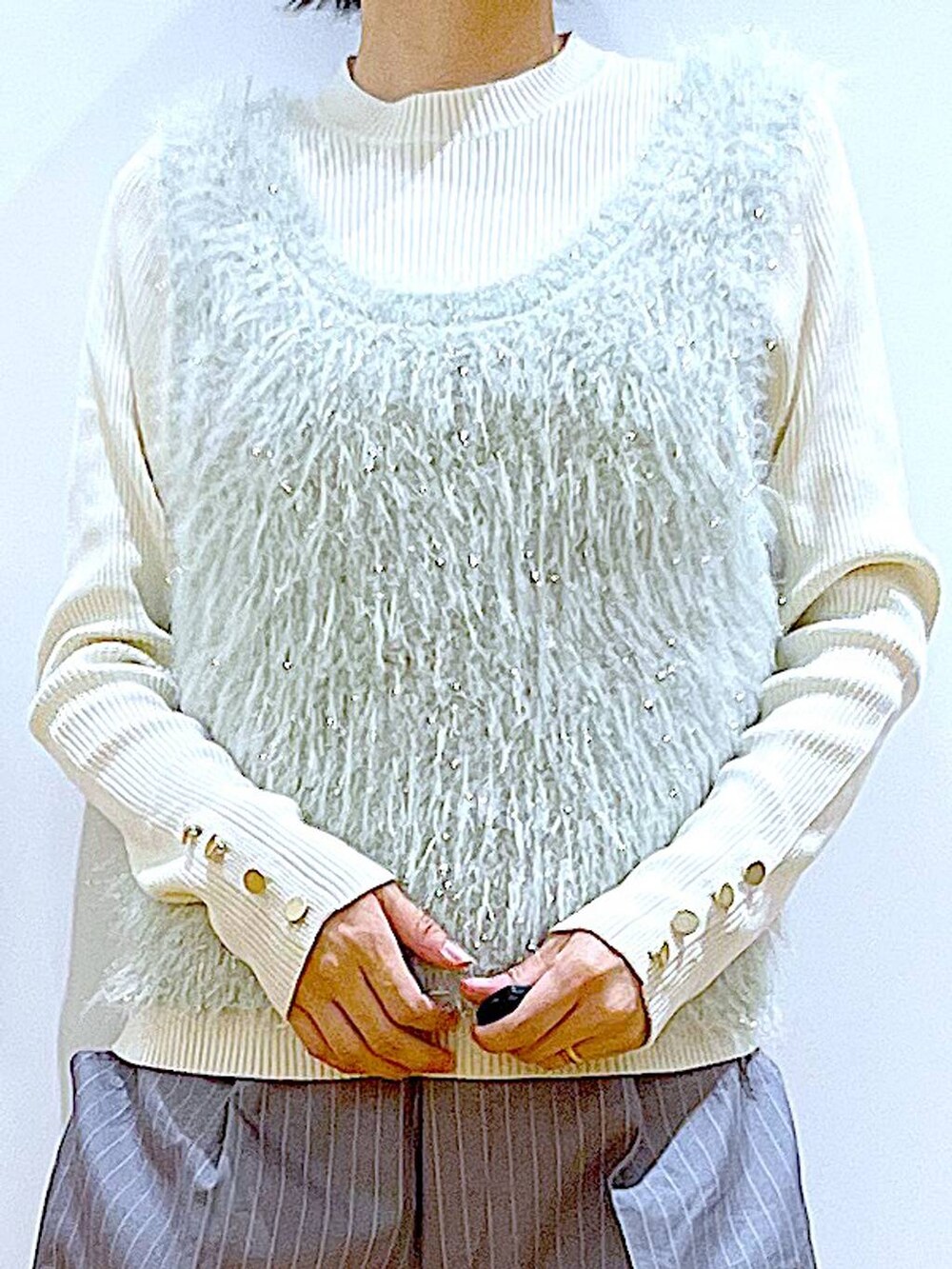 ホワイト系のニット/セーター、ホワイト系のハンドバッグ、グレー系のスラックスを着用したレディースの秋コーディネートの7枚目の写真