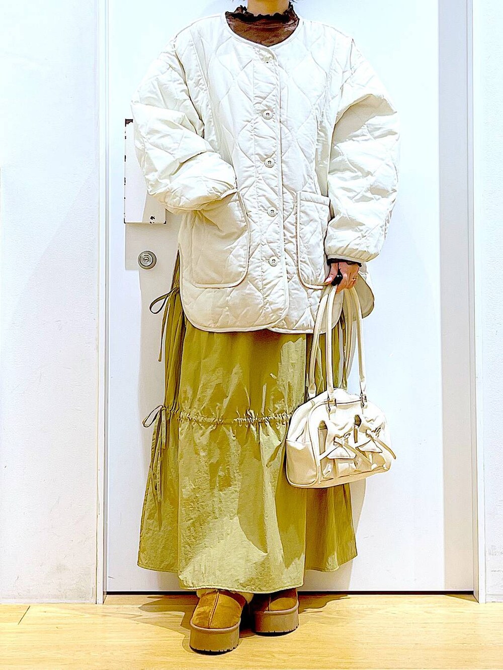 ベージュ系のブルゾン、ベージュ系のスリッポン、ホワイト系のハンドバッグを着用したレディースの秋コーディネートの6枚目の写真