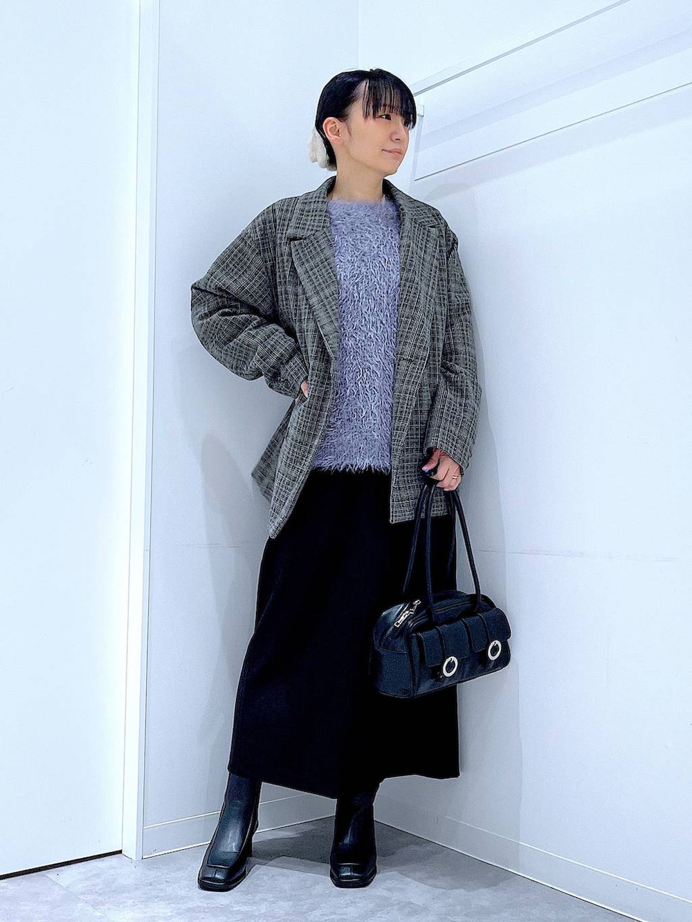 ブラック系のショルダーバッグ、ブラック系のスカート、ブラック系のブーツを着用したレディースの冬コーディネートの2枚目の写真