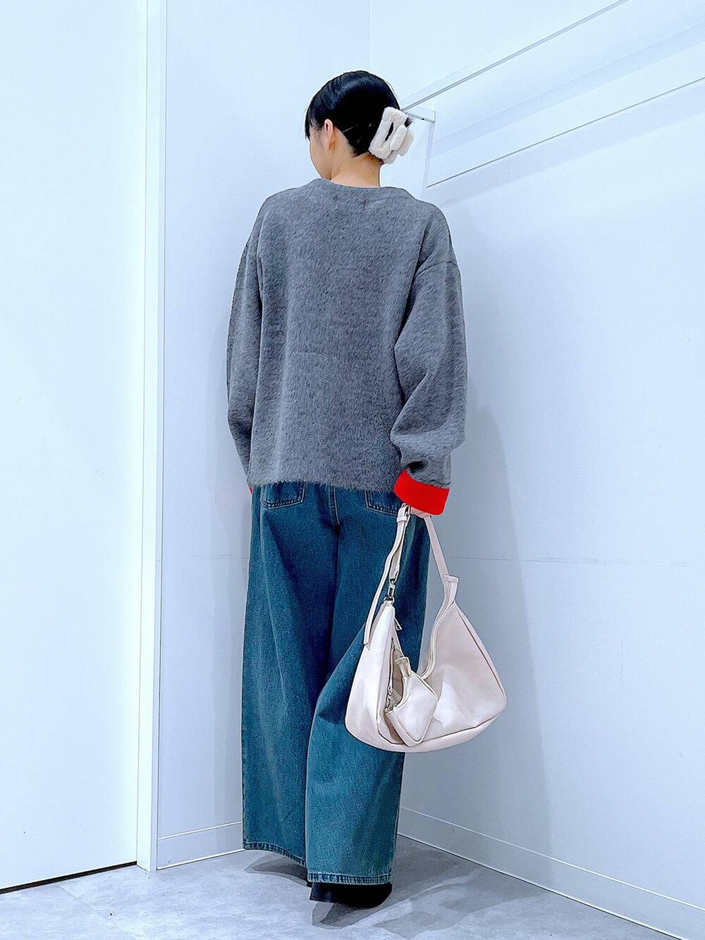 ブルー系のデニムパンツ、ブラック系のブーツ、ホワイト系のショルダーバッグを着用したレディースの冬コーディネートの5枚目の写真