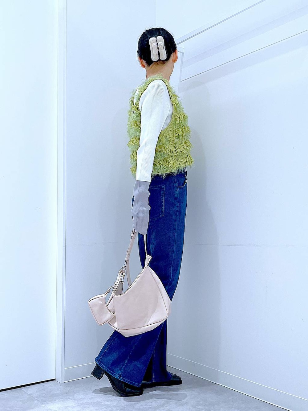 ブラック系のブーツ、ホワイト系のショルダーバッグ、グリーン系のベストを着用したレディースの春コーディネートの4枚目の写真