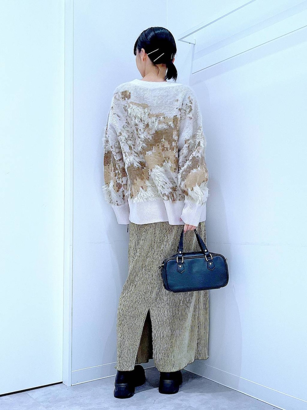 ブラック系のブーツ、ブラック系のショルダーバッグ、グリーン系のスカートを着用したレディースの冬コーディネートの5枚目の写真