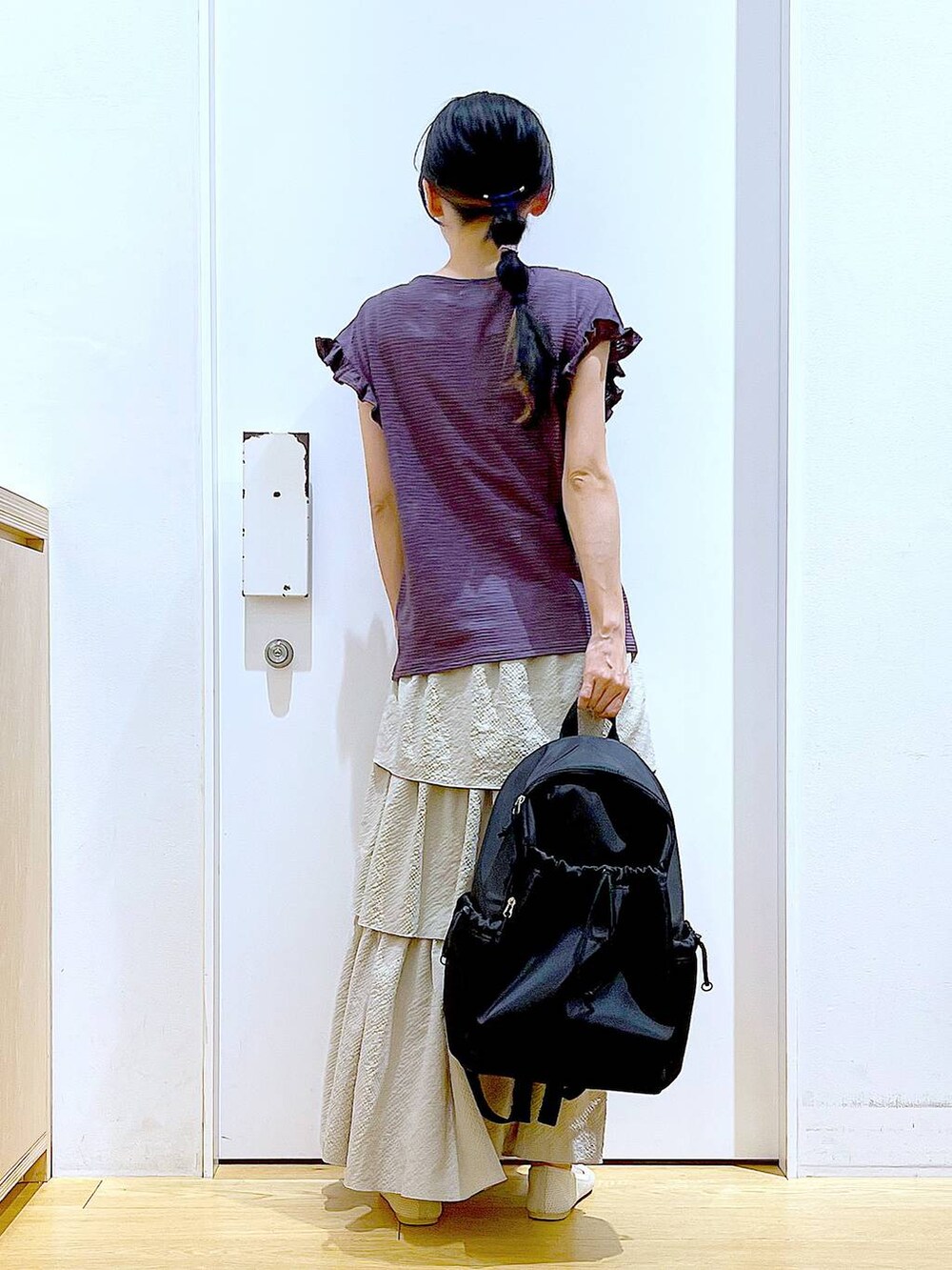 ブラウン系のTシャツ/カットソー、ベージュ系のスカート、ブラック系のバックパック/リュックを着用したレディースの春コーディネートの5枚目の写真