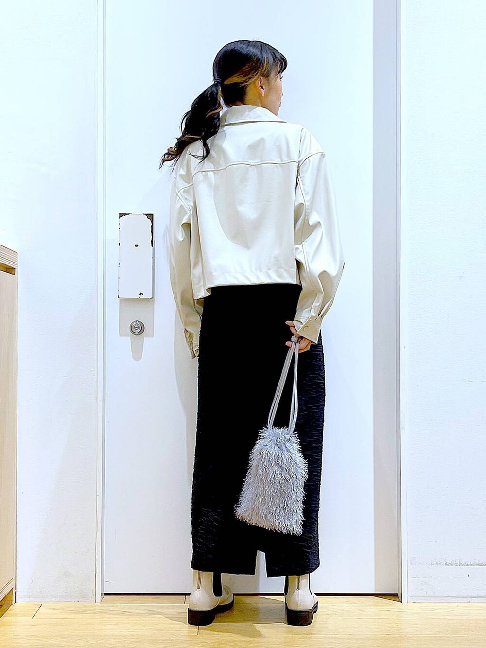 ブラック系のスカート、ベージュ系のブルゾン、ベージュ系のブーツを着用したレディースの春コーディネートの5枚目の写真