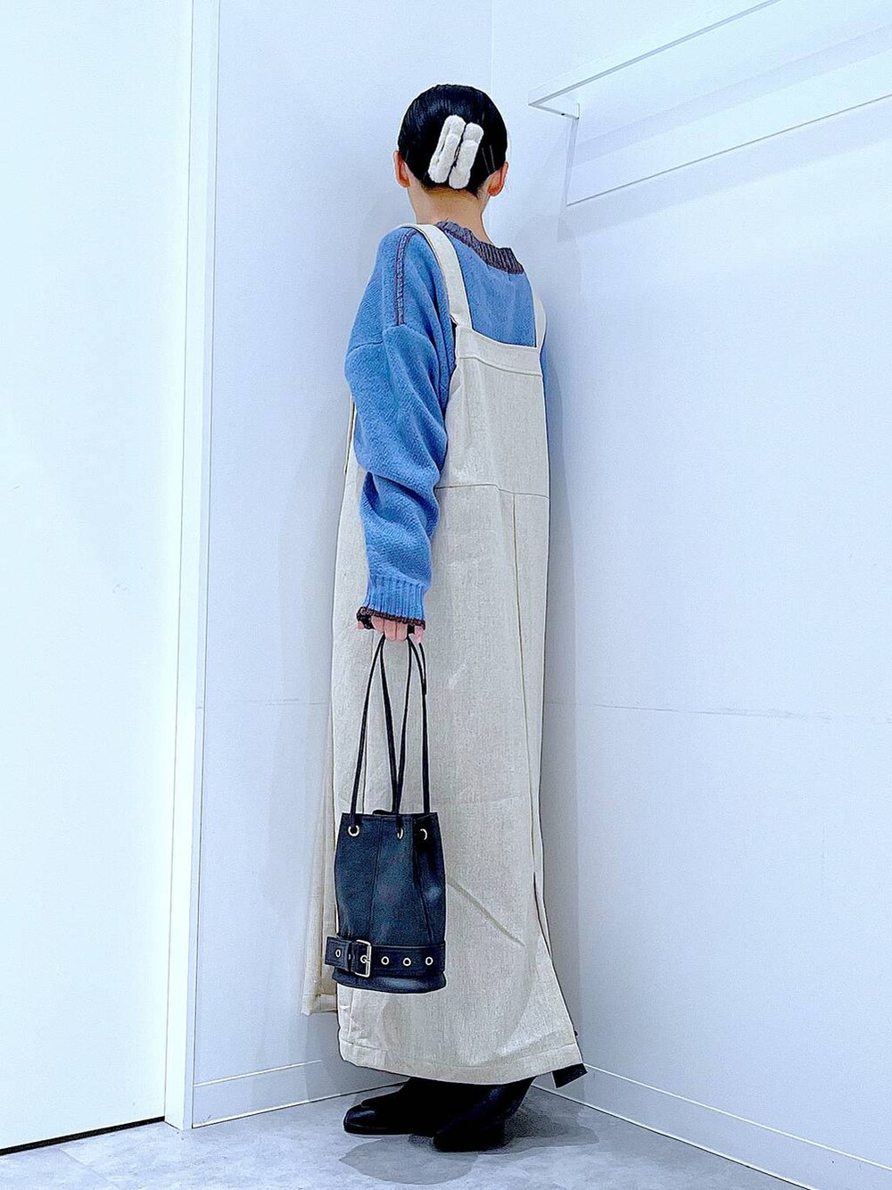 ブラック系のブーツ、ブラック系のハンドバッグ、ブルー系のニット/セーターを着用したレディースの秋コーディネートの3枚目の写真