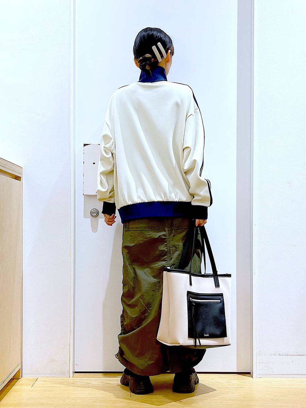 ホワイト系のトートバッグ、ブラック系のブーツ、グリーン系のスカートを着用したレディースの冬コーディネートの5枚目の写真