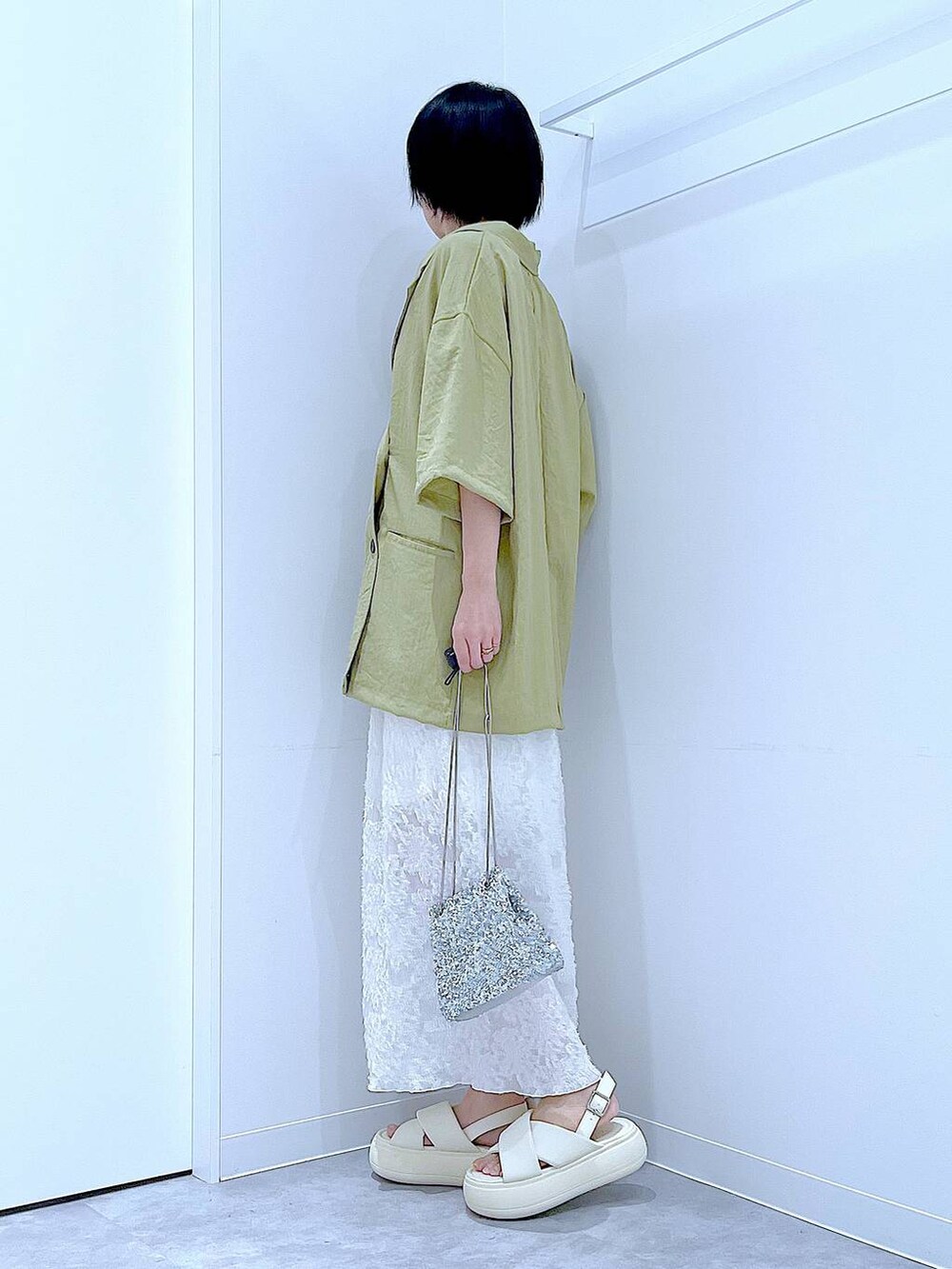 シルバー系のショルダーバッグ、ホワイト系のサンダル、グリーン系のテーラードジャケットを着用したレディースの夏コーディネートの3枚目の写真