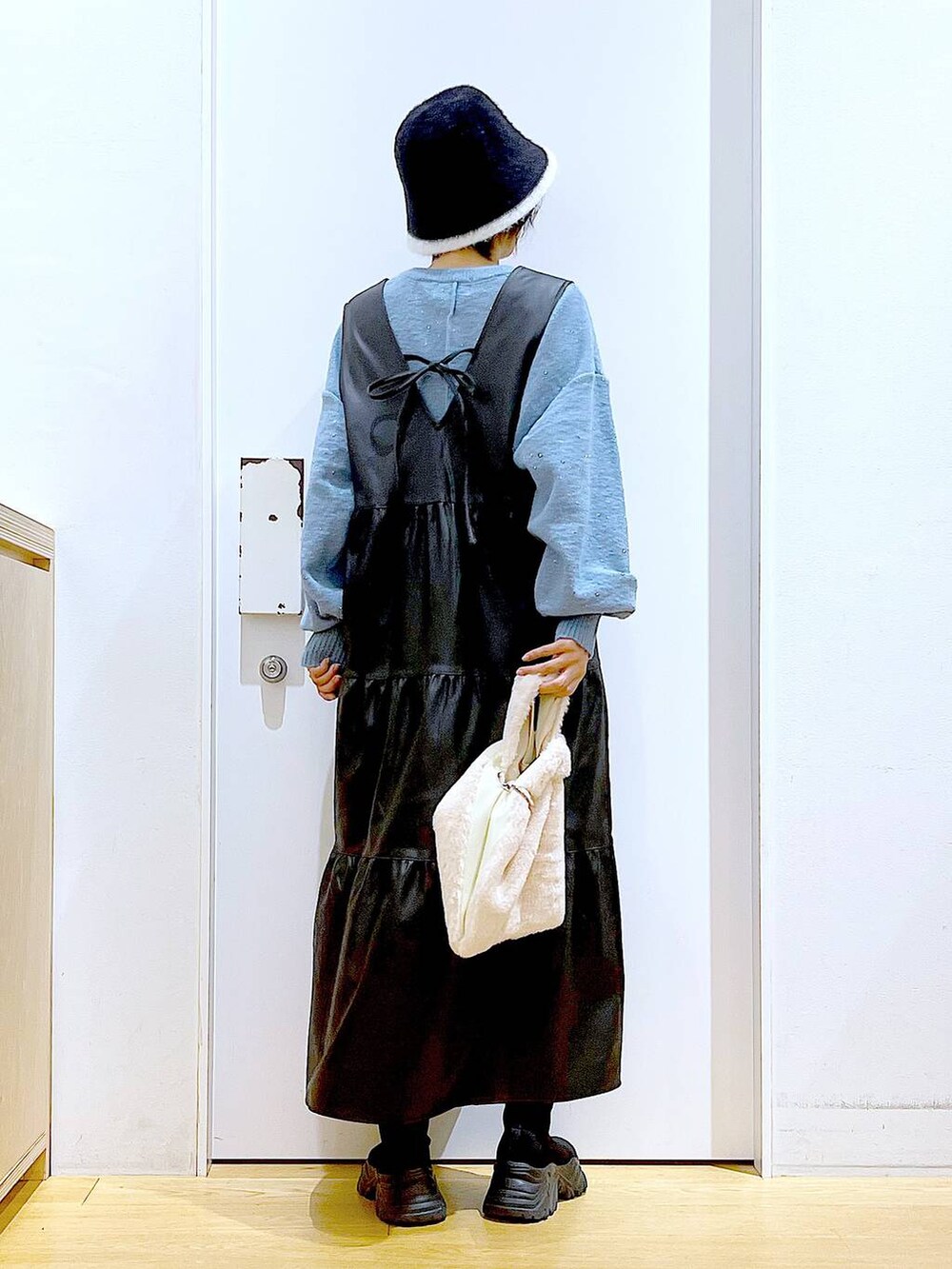 ホワイト系のショルダーバッグ、ブラック系のブーツ、ブラック系のワンピースを着用したレディースの冬コーディネートの5枚目の写真