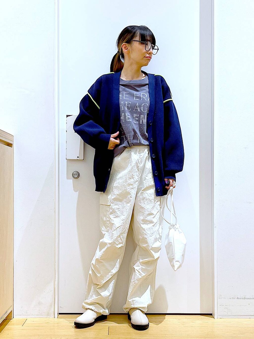 グレー系のTシャツ/カットソー、ベージュ系のブーツ、ホワイト系のショルダーバッグを着用したレディースの冬コーディネートの2枚目の写真