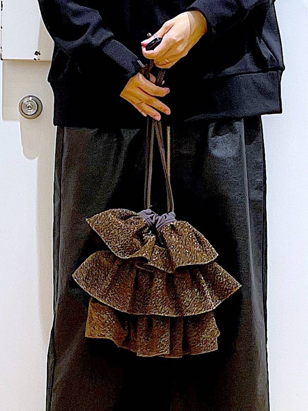 ブラック系のスカート、ブラック系のブーツ、ブラウン系のショルダーバッグを着用したレディースの冬コーディネートの9枚目の写真