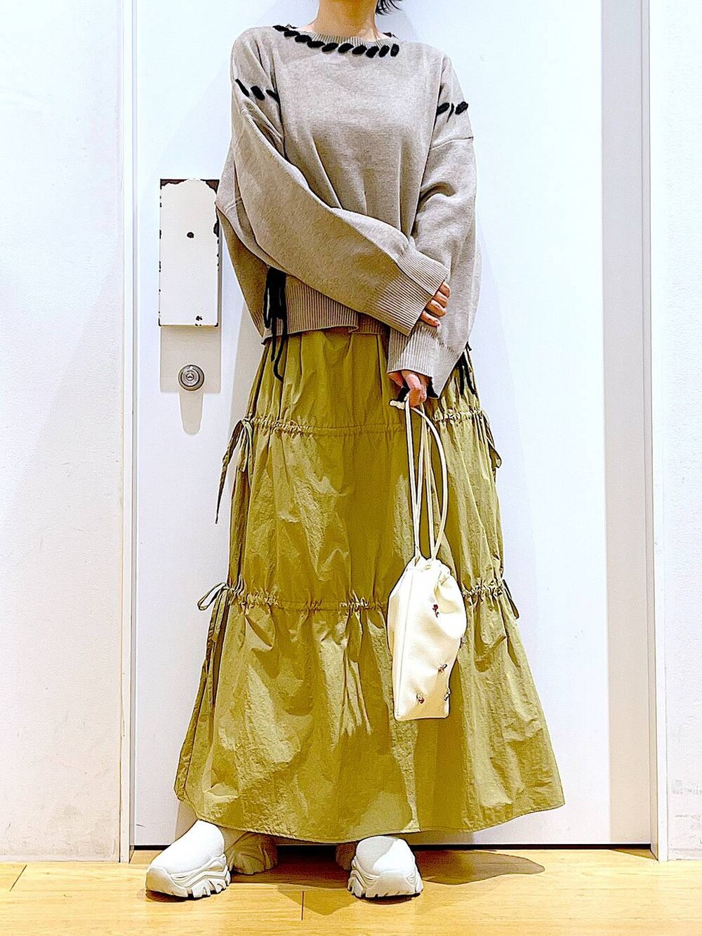 ホワイト系のショルダーバッグ、イエロー系のスカート、ベージュ系のブーツを着用したレディースの秋コーディネートの6枚目の写真