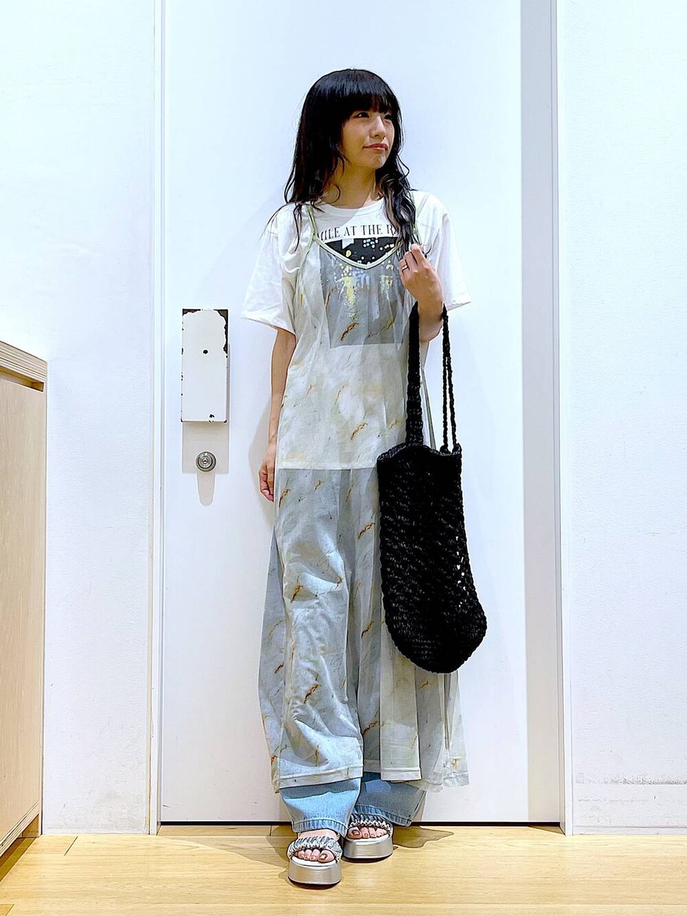 ブルー系のデニムパンツ、ブラック系のトートバッグ、ホワイト系のTシャツ/カットソーを着用したレディースの夏コーディネートの2枚目の写真