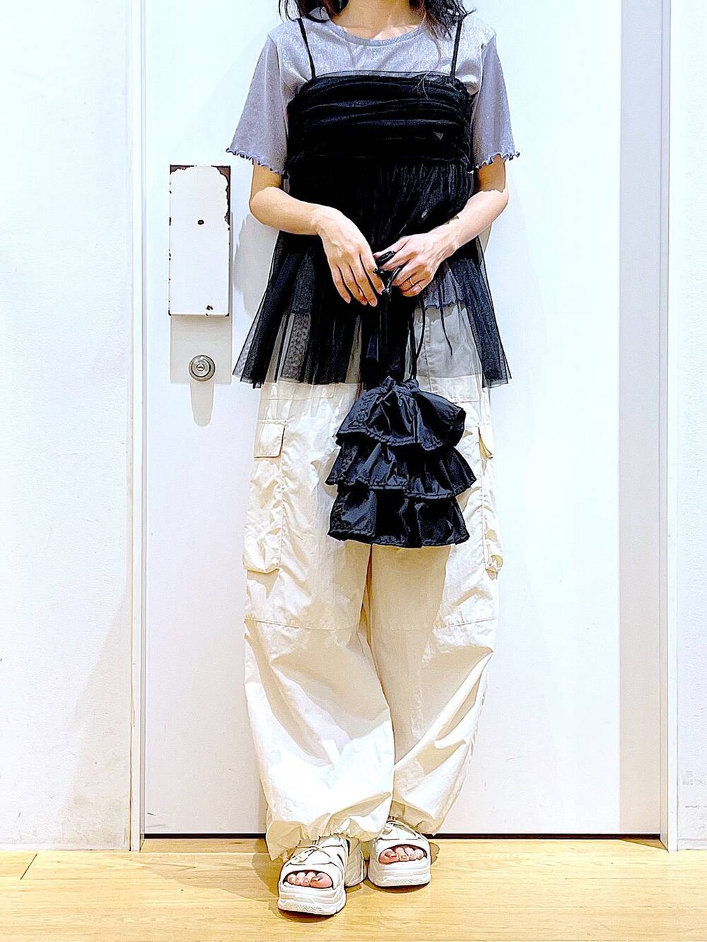 ブラック系のショルダーバッグ、ホワイト系のカーゴパンツ、ブラック系のキャミソールを着用したレディースの夏コーディネートの6枚目の写真