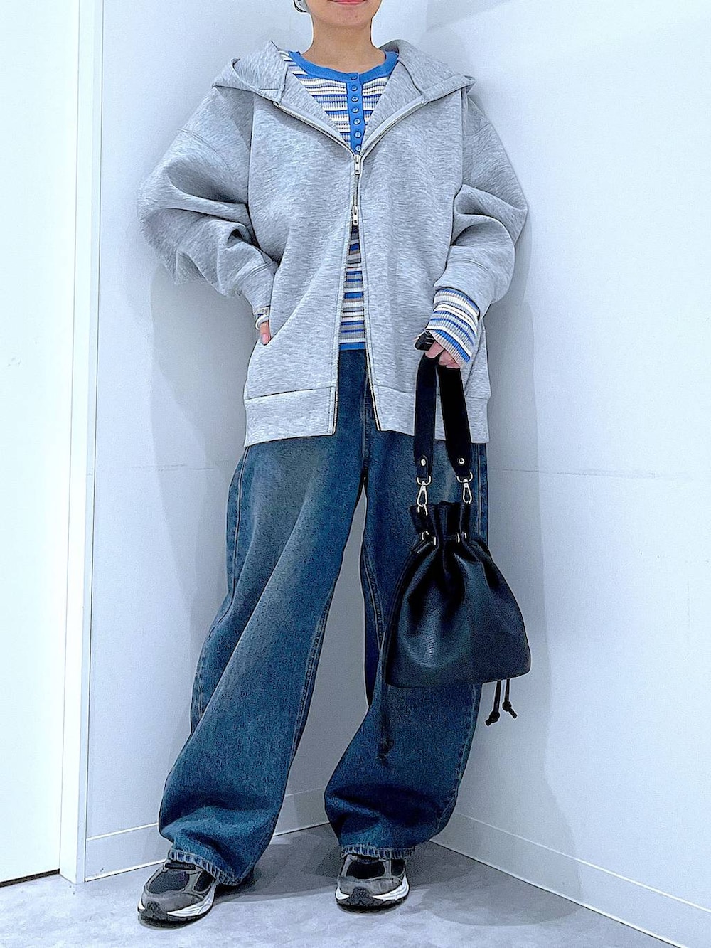 ブルー系のデニムパンツ、グレー系のパーカー、ブラック系のショルダーバッグを着用したレディースの冬コーディネートの6枚目の写真