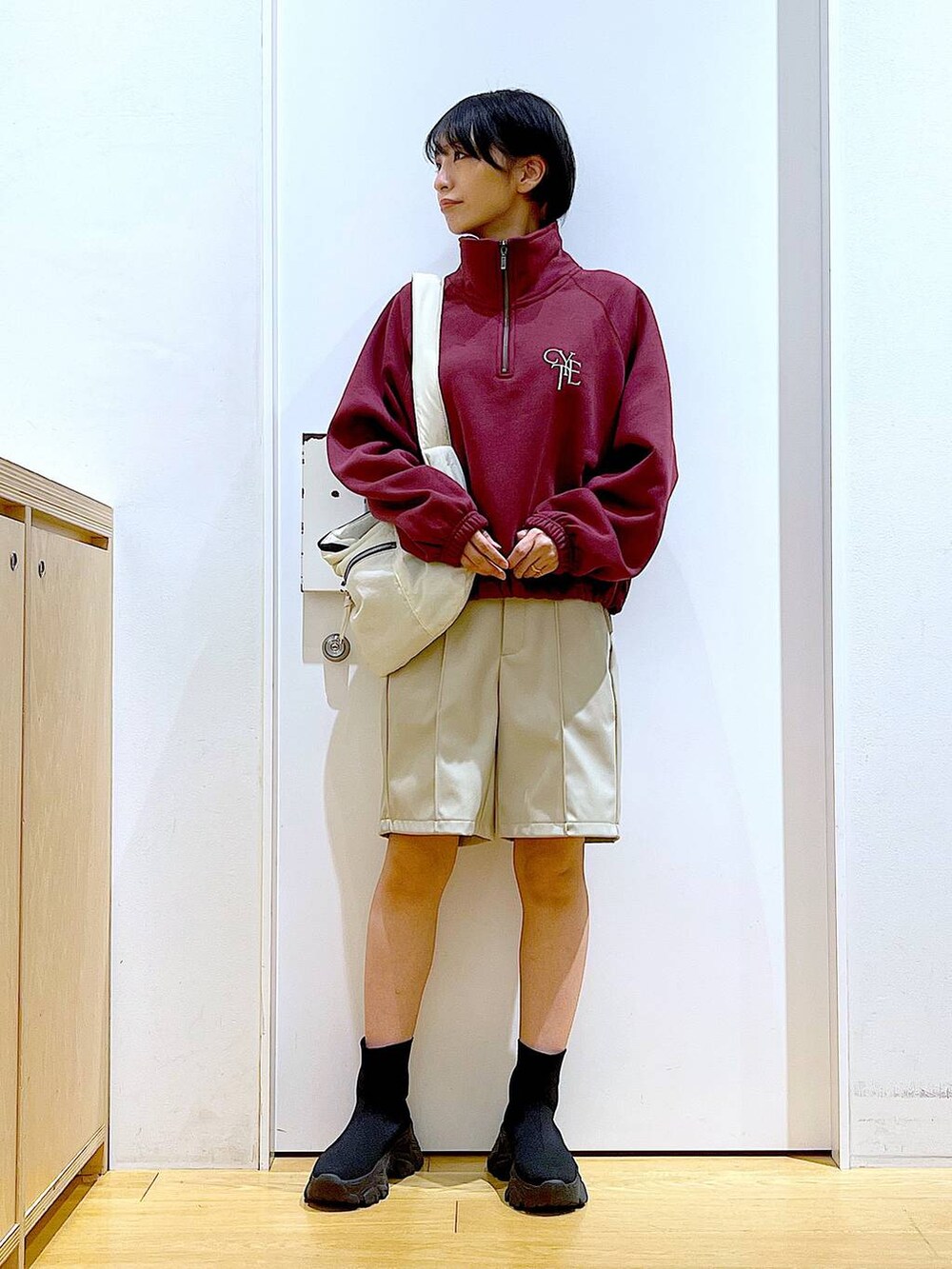 ホワイト系のショルダーバッグ、ブラック系のブーツ、レッド系のスウェットを着用したレディースの冬コーディネートの2枚目の写真