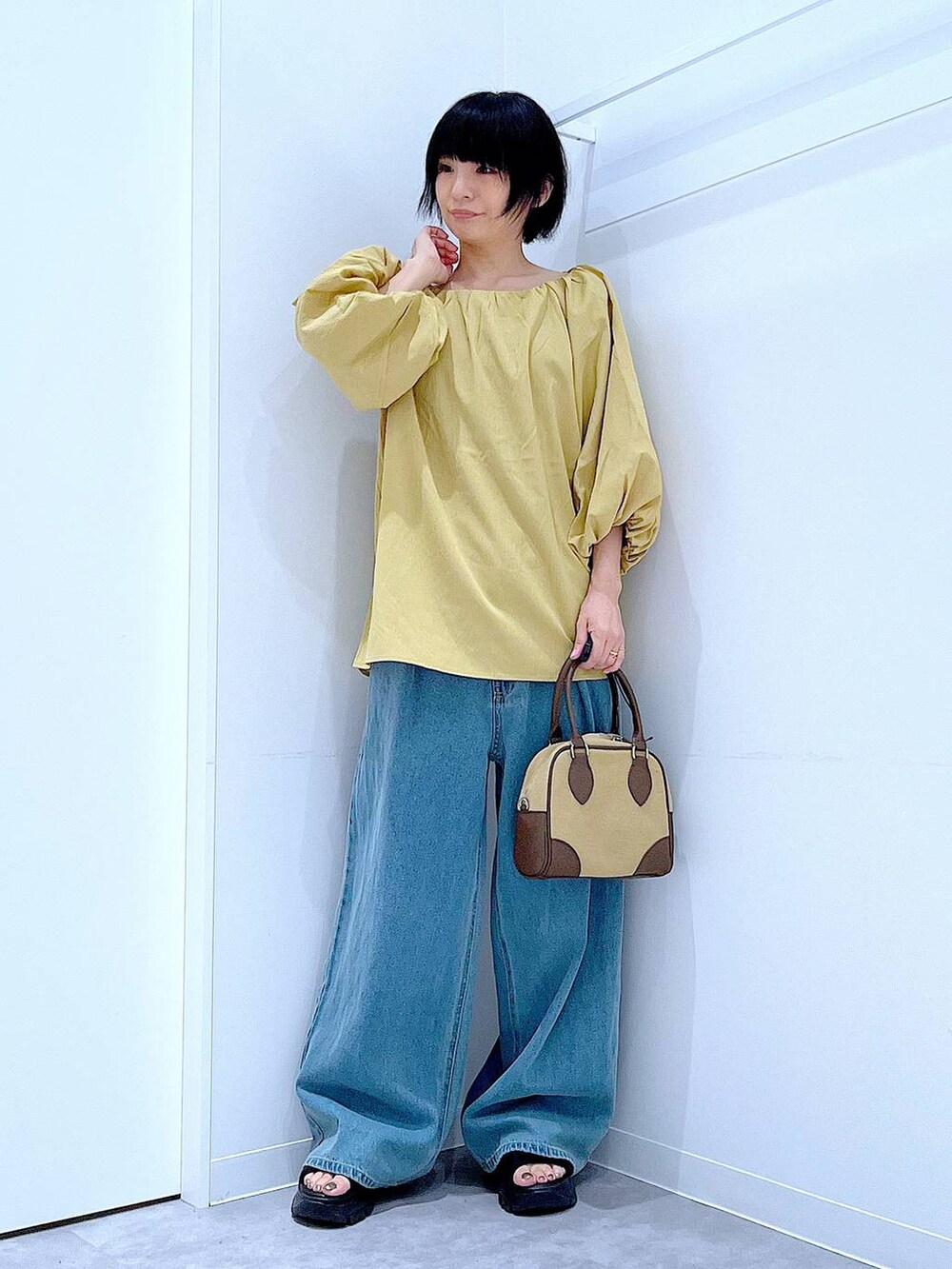 ブラック系のスニーカー、ブルー系のデニムパンツ、イエロー系のシャツ/ブラウスを着用したレディースの秋コーディネートの2枚目の写真