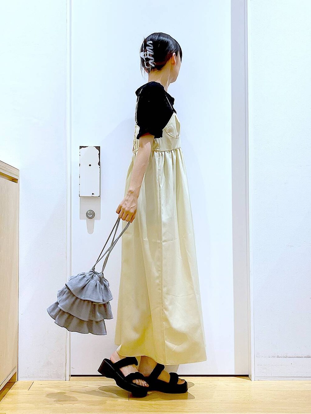 ブラック系のサンダル、イエロー系のワンピース、ブラック系のカーディガン/ボレロを着用したレディースの夏コーディネートの4枚目の写真