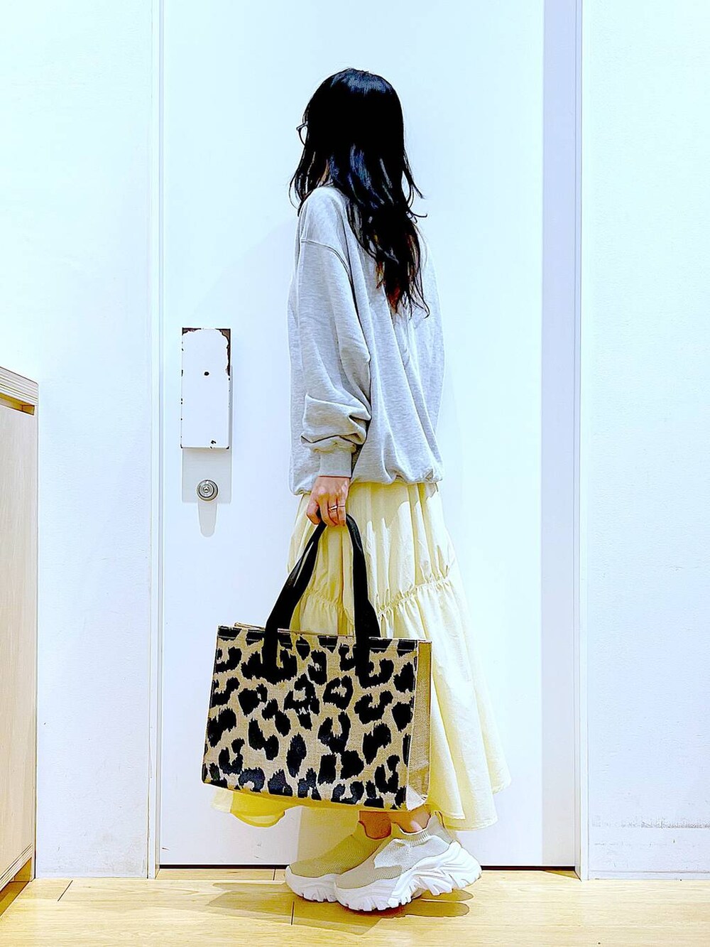 グレー系のスウェット、ベージュ系のスニーカー、イエロー系のスカートを着用したレディースの春コーディネートの3枚目の写真