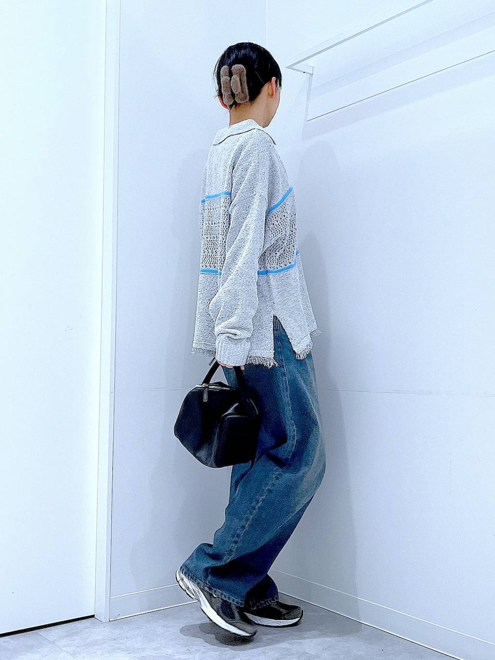 ブルー系のデニムパンツ、ブラック系のTシャツ/カットソー、ブラック系のショルダーバッグを着用したレディースの冬コーディネートの4枚目の写真