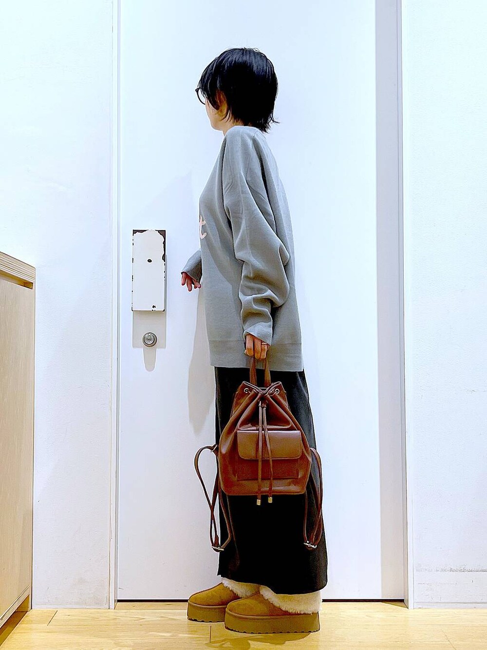 グレー系のニット/セーター、ブラウン系のバックパック/リュック、ブラック系のスカートを着用したレディースの冬コーディネートの3枚目の写真