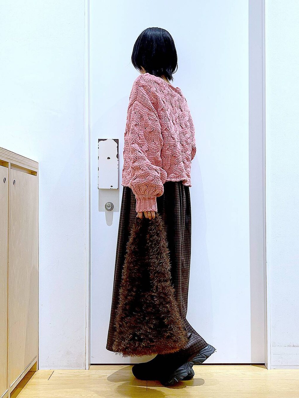 ブラック系のブーツ、ブラウン系のショルダーバッグ、ピンク系のニット/セーターを着用したレディースの冬コーディネートの3枚目の写真