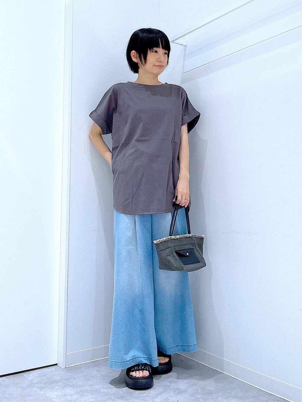 ブラック系のショルダーバッグ、ブラック系のサンダル、ブルー系のデニムパンツを着用したレディースの夏コーディネートの2枚目の写真