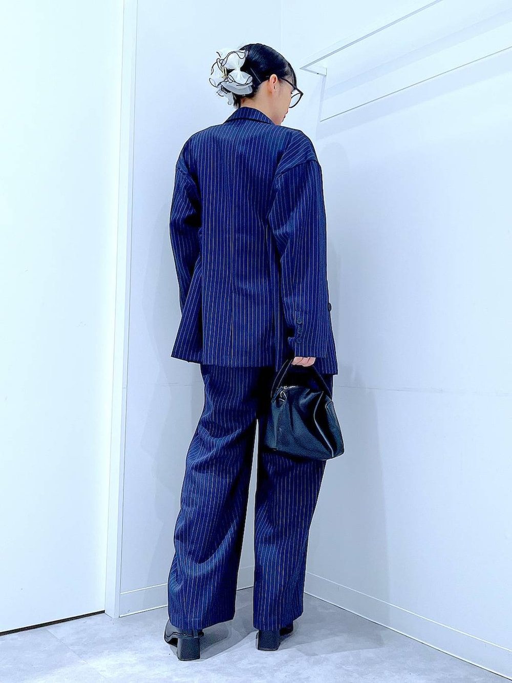 ブラック系のブーツ、ブラック系のショルダーバッグ、ブルー系のスラックスを着用したレディースの冬コーディネートの5枚目の写真