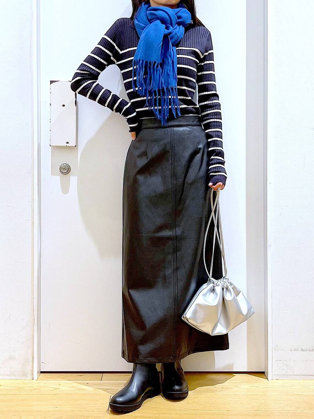ブラック系のブーツ、ブルー系のニット/セーター、シルバー系のショルダーバッグを着用したレディースの冬コーディネートの6枚目の写真