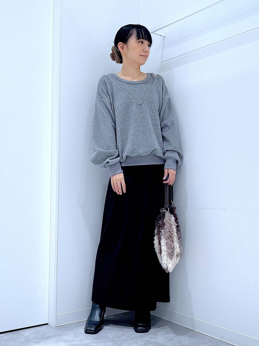 ブラック系のスカート、ブラック系のブーツ、ブラウン系のショルダーバッグを着用したレディースの冬コーディネートの2枚目の写真