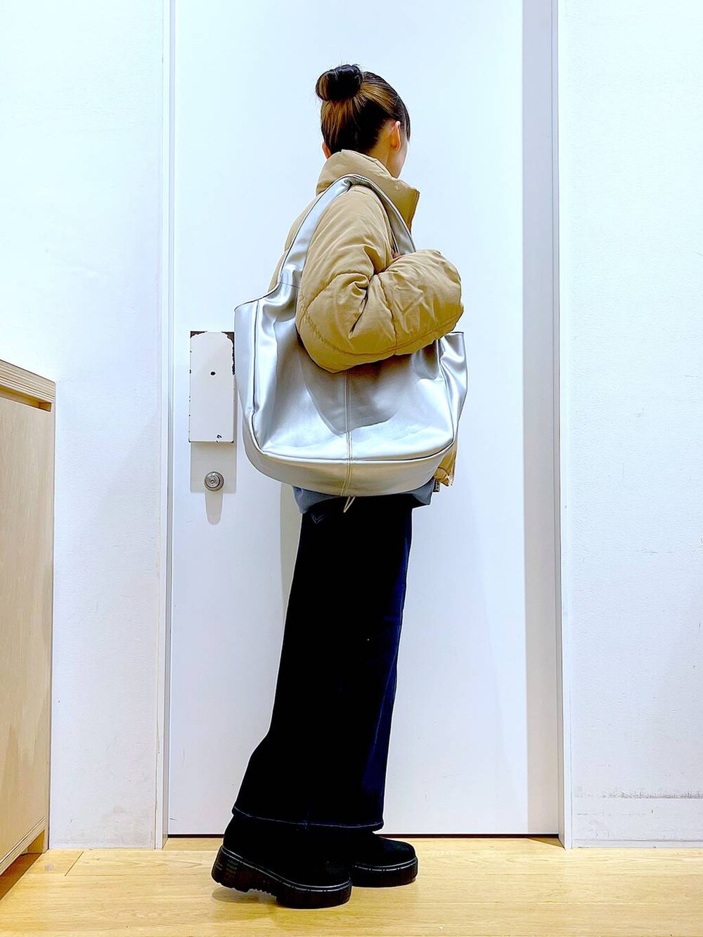 シルバー系のトートバッグ、ベージュ系のナイロンジャケット、ブルー系のデニムスカートを着用したレディースの冬コーディネートの4枚目の写真