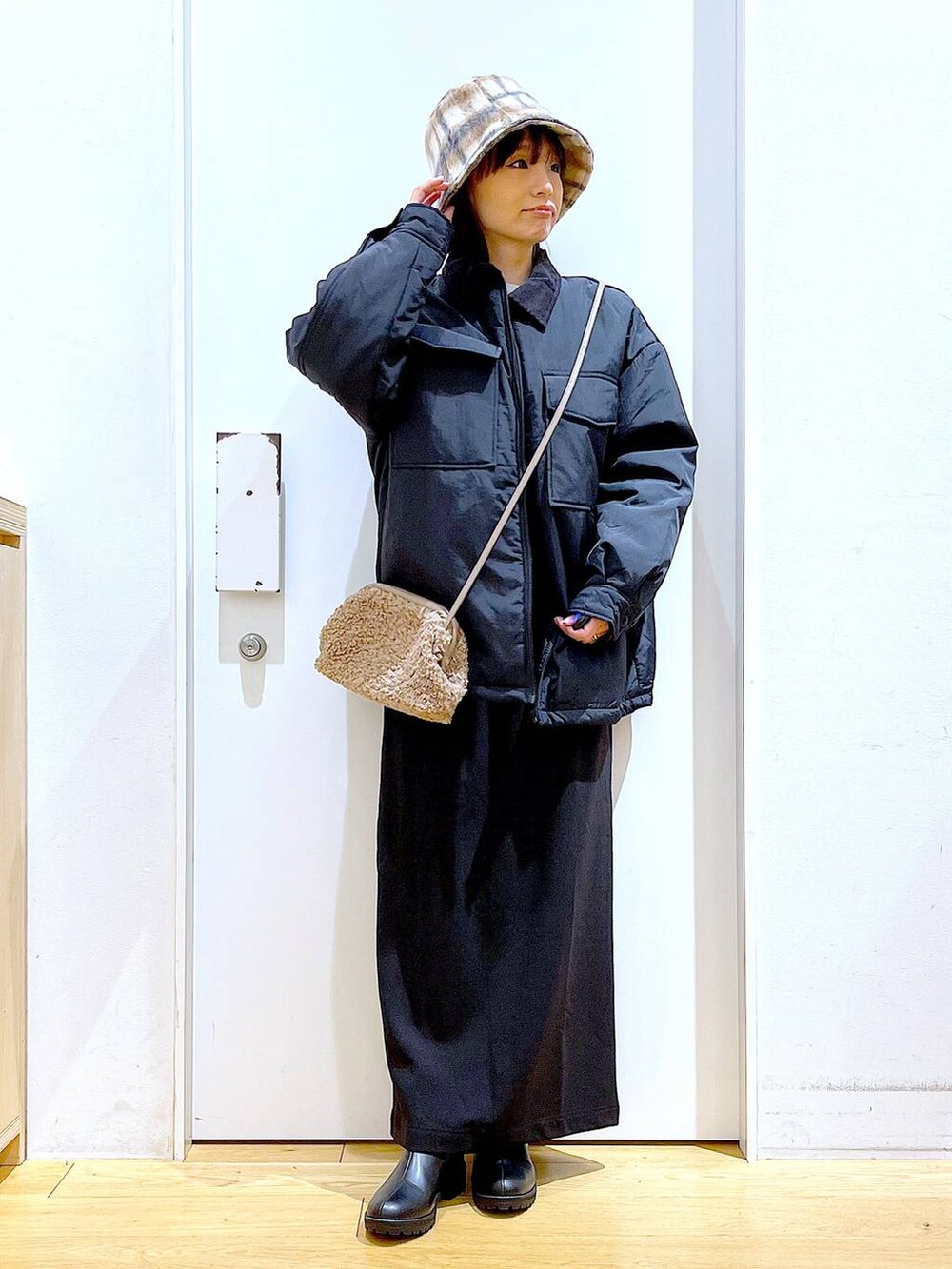 ブラック系のブルゾン、ブラック系のブーツ、ブラウン系のクラッチバッグを着用したレディースの冬コーディネートの2枚目の写真