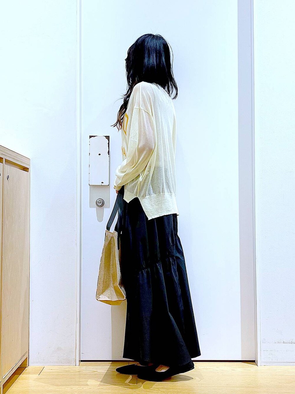 ホワイト系のニット/セーター、ブラック系のスカート、ブラック系のパンプスを着用したレディースの夏コーディネートの3枚目の写真