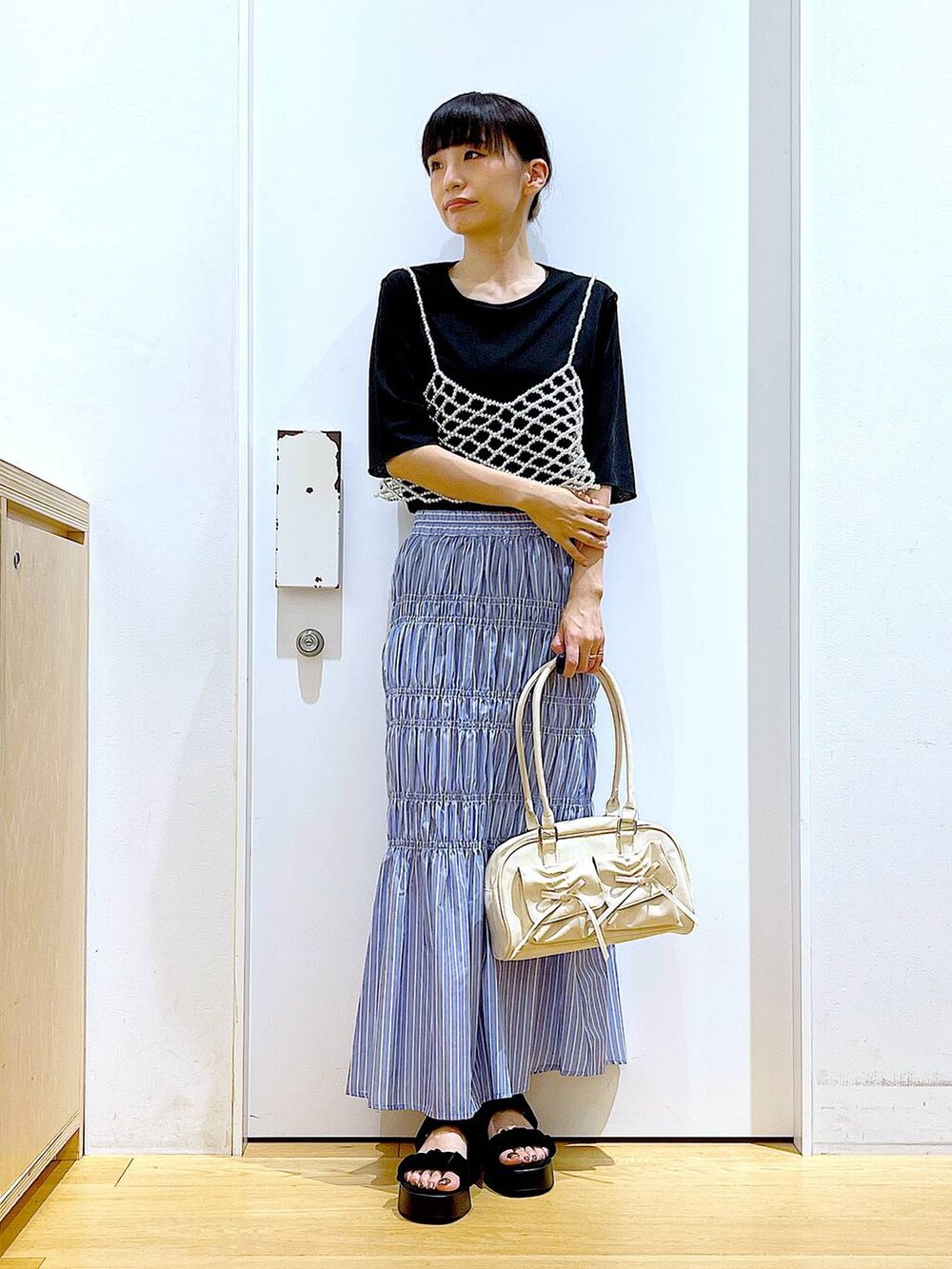 ブラック系のサンダル、ホワイト系のベスト、その他のスカートを着用したレディースの夏コーディネートの2枚目の写真