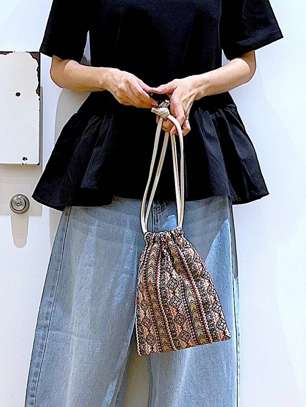 ピンク系のショルダーバッグ、ブルー系のデニムパンツ、ブラック系のTシャツ/カットソーを着用したレディースの夏コーディネートの9枚目の写真