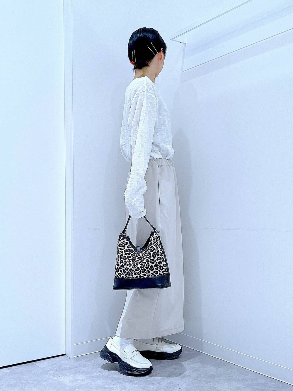 ベージュ系のスカート、ホワイト系のローファー、その他のショルダーバッグを着用したレディースの秋コーディネートの4枚目の写真