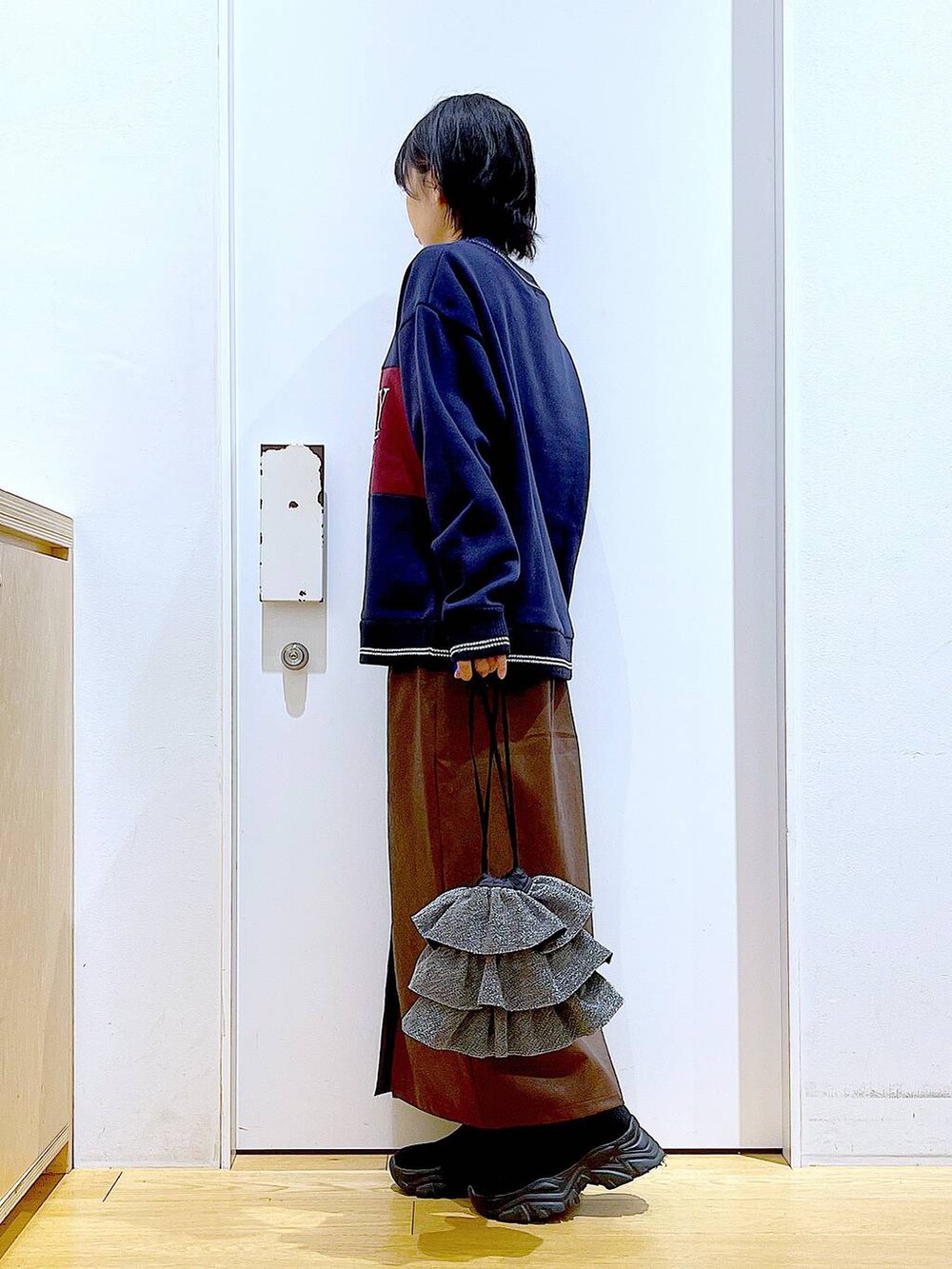 ブラウン系のスカート、ブラック系のブーツ、シルバー系のショルダーバッグを着用したレディースの冬コーディネートの3枚目の写真