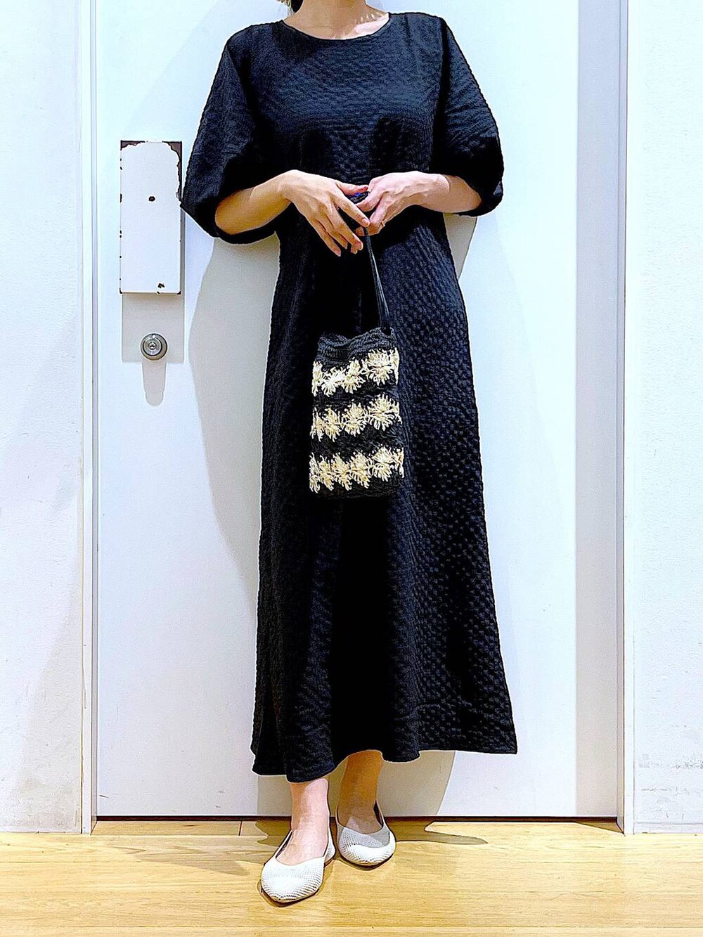 ホワイト系のパンプス、ブラック系のショルダーバッグ、ブラック系のワンピースを着用したレディースの夏コーディネートの3枚目の写真