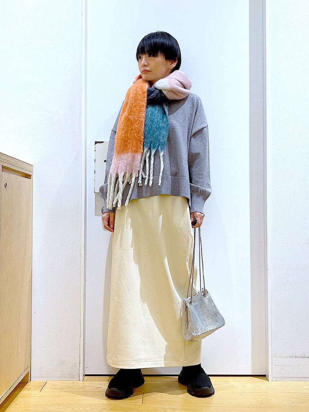 ブラック系のブーツ、ホワイト系のスカート、グレー系のニット/セーターを着用したレディースの冬コーディネートの2枚目の写真