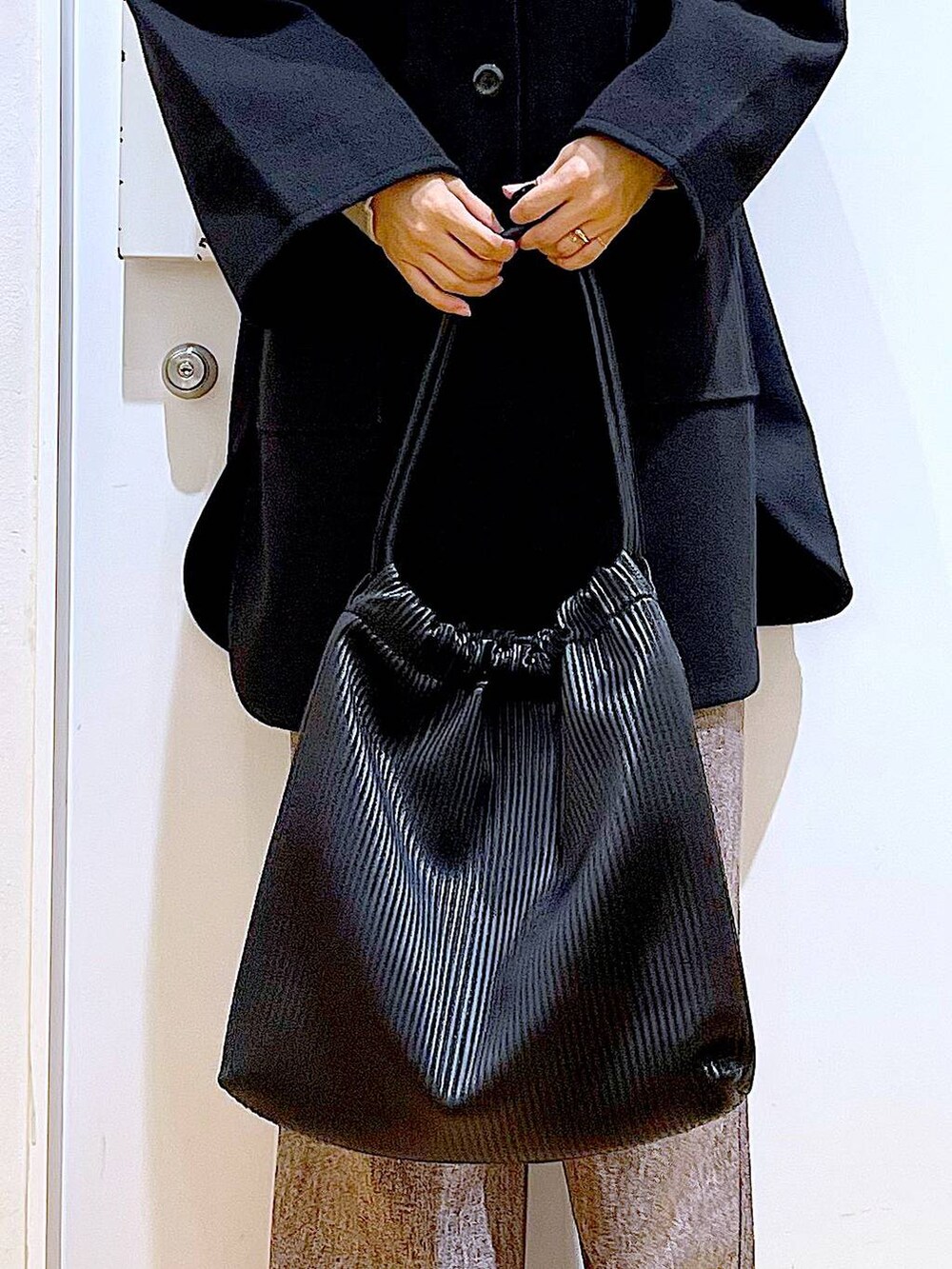 ブラック系のその他アウター、ブラック系のブーツ、ブラック系のトートバッグを着用したレディースの冬コーディネートの9枚目の写真