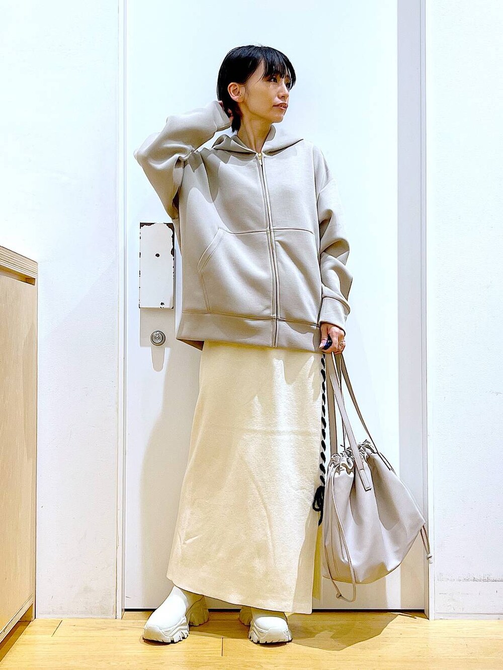 ベージュ系のトートバッグ、ベージュ系のブーツ、ベージュ系のスカートを着用したレディースの秋コーディネートの2枚目の写真