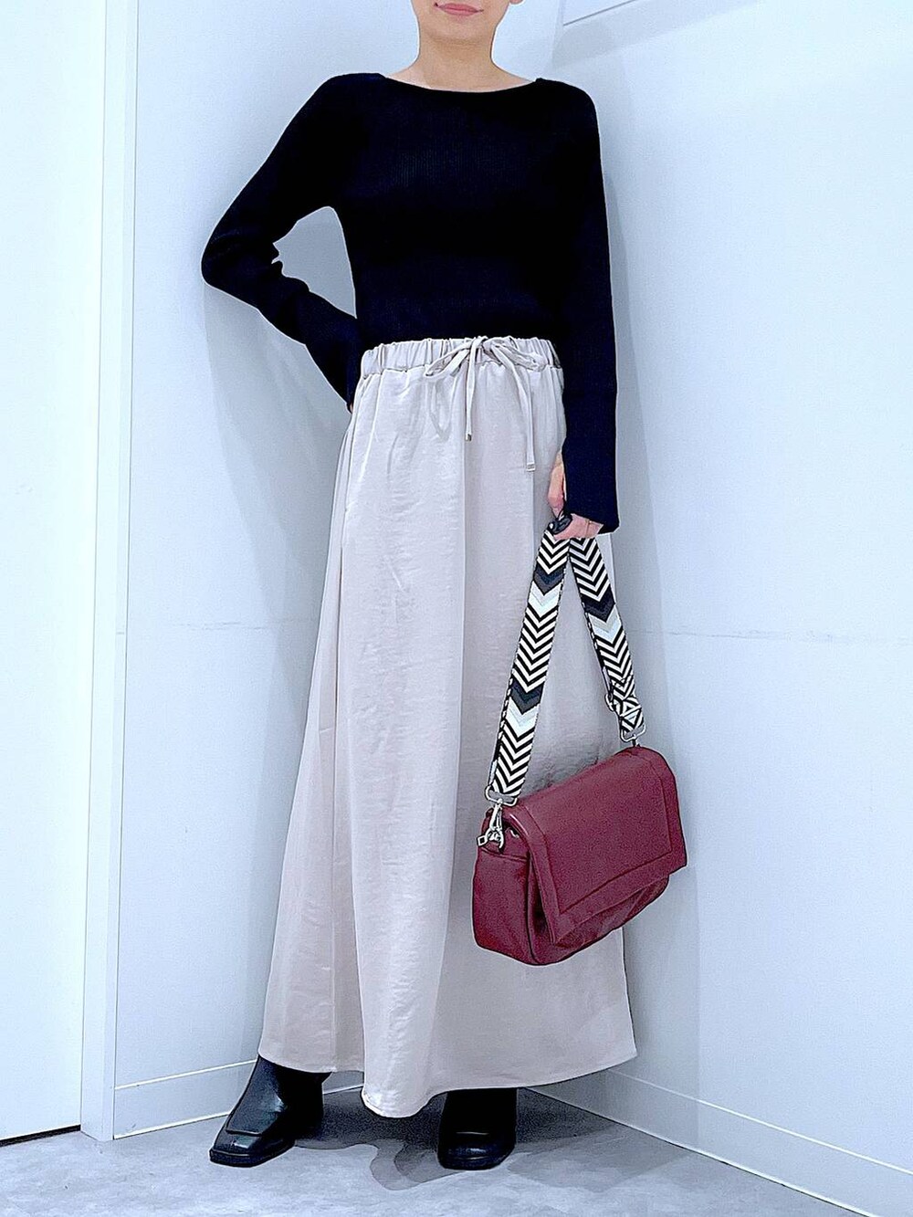 ブラック系のニット/セーター、ベージュ系のスカート、レッド系のショルダーバッグを着用したレディースの秋コーディネートの6枚目の写真