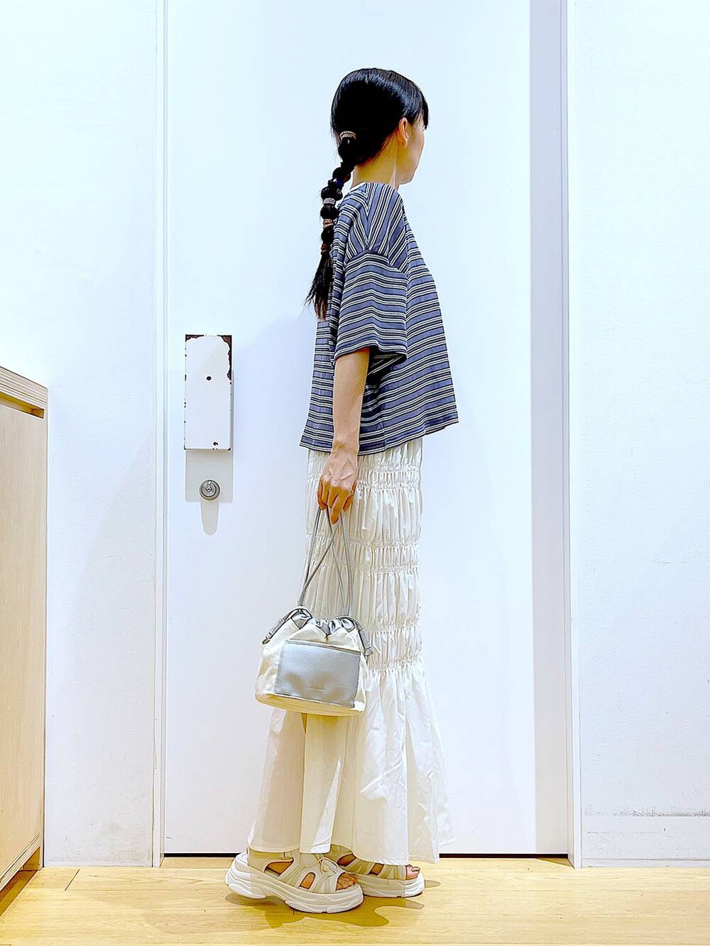 ホワイト系のショルダーバッグ、ホワイト系のサンダル、グレー系のTシャツ/カットソーを着用したレディースの夏コーディネートの4枚目の写真