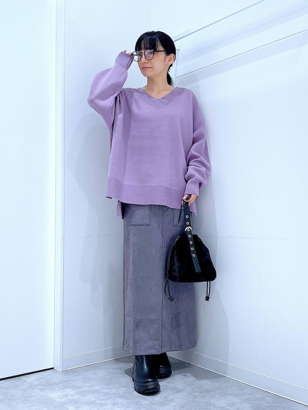 ブラック系のハンドバッグ、ブラック系のブーツ、グレー系のスカートを着用したレディースの冬コーディネートの2枚目の写真